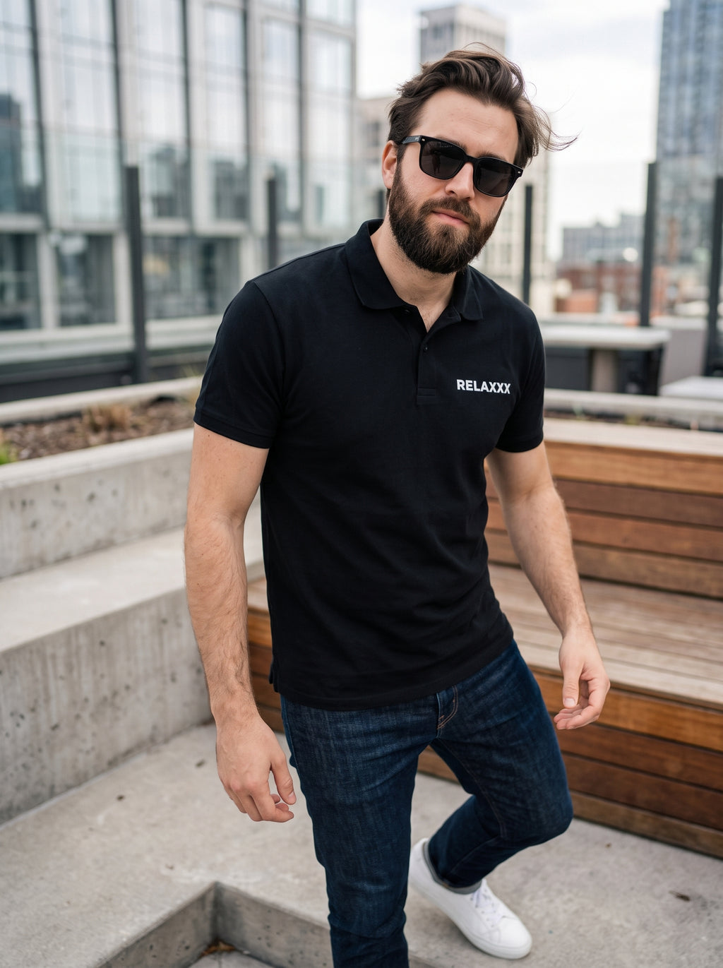RELAXXX Polo — black polo shirt with RELAXXX chest print worn by man on rooftop