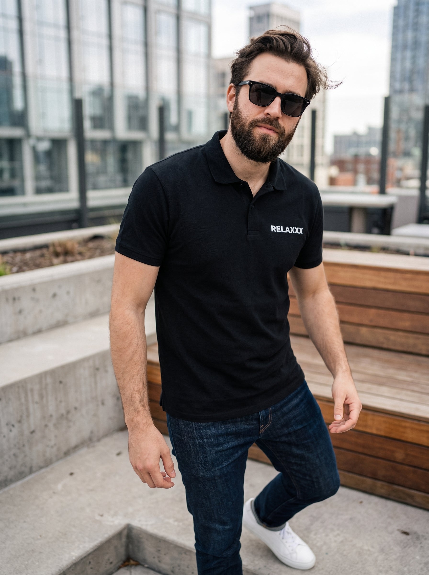 RELAXXX Polo — black polo shirt with RELAXXX chest print worn by man on rooftop