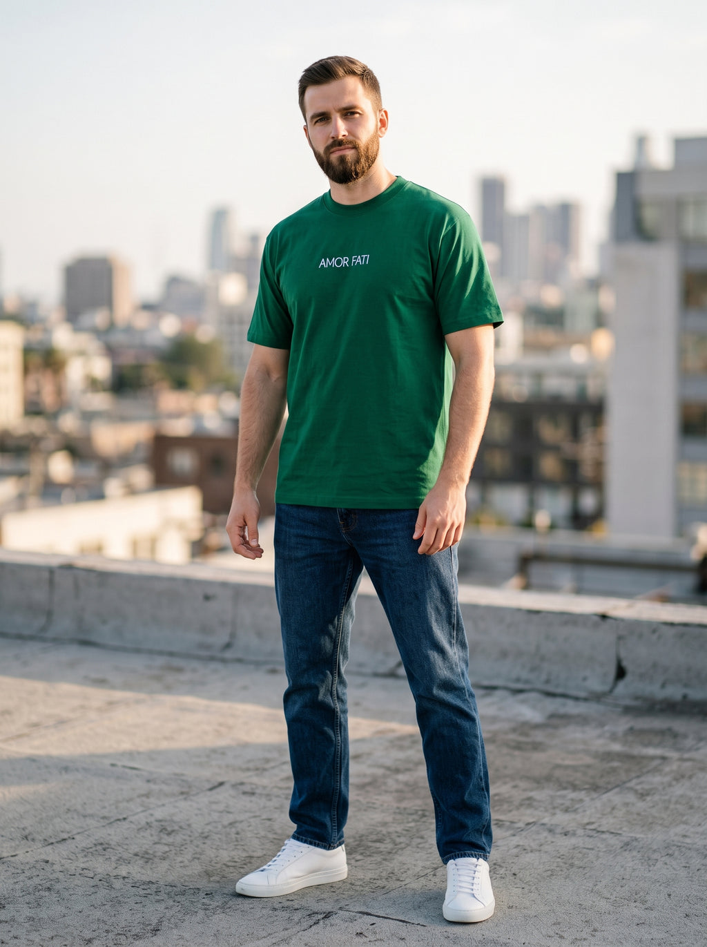 Amor Fati Tee — forest green t-shirt with minimal white AMOR FATI chest print worn by man on rooftop