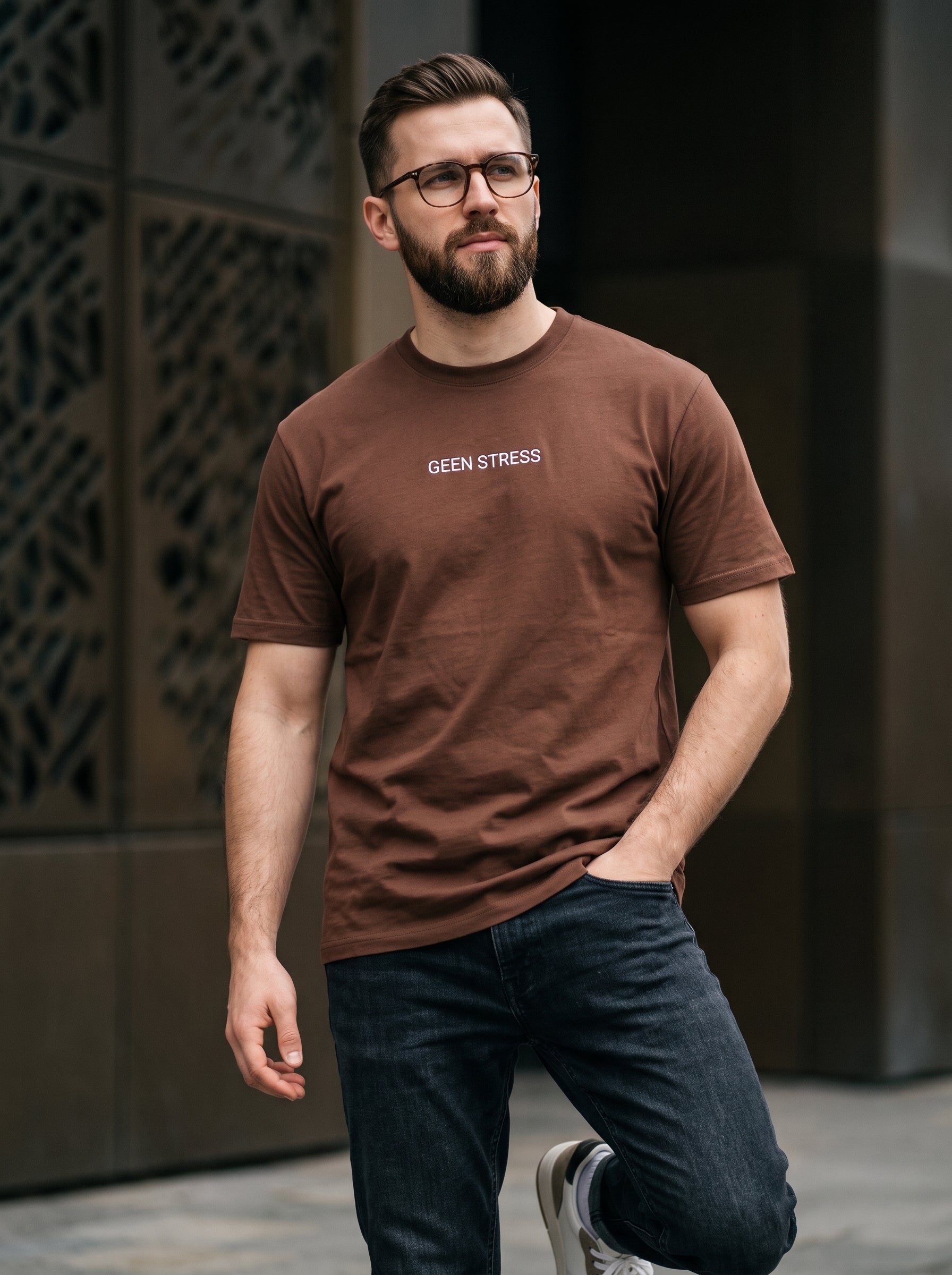 Geen Stress Tee — chocolate brown t-shirt with white GEEN STRESS print worn by man on street