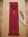 Macrame Fringe Belt in Burgundy — flat lay on wooden surface with eucalyptus branch