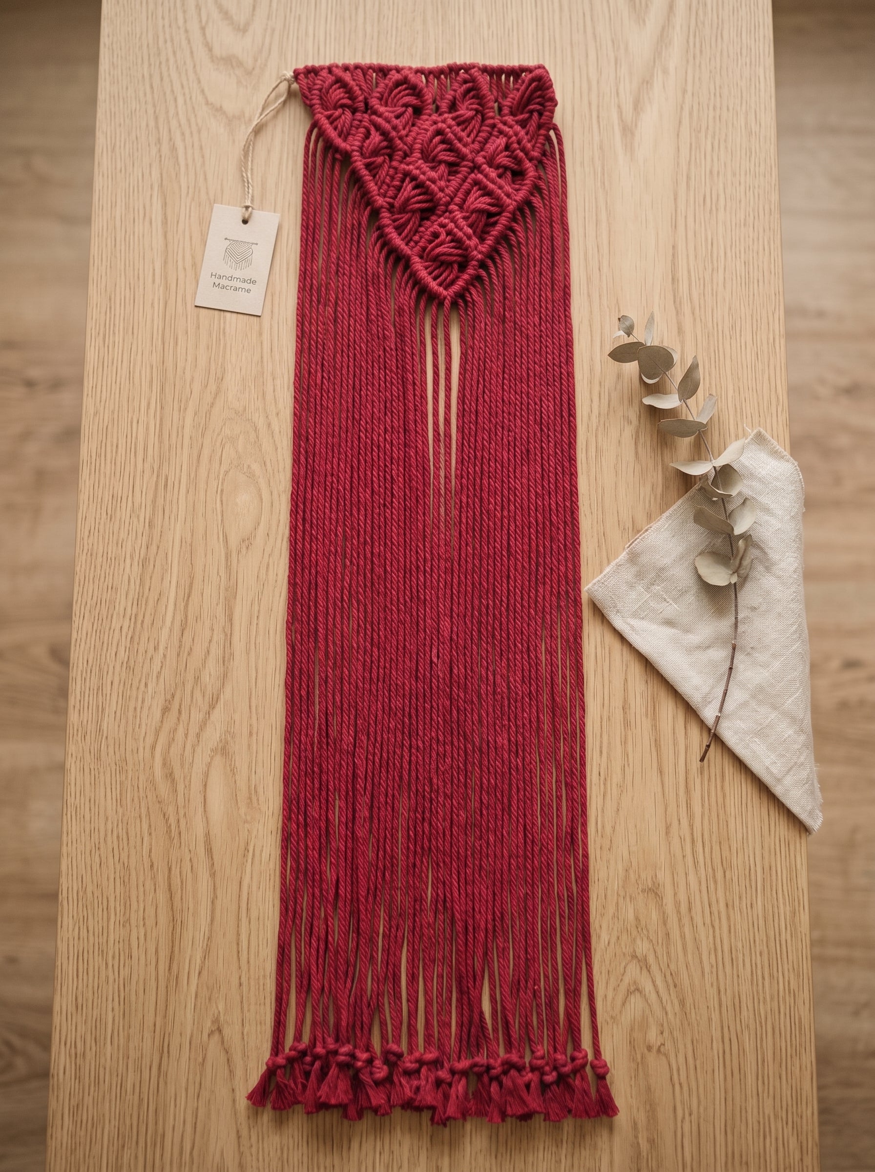 Macrame Fringe Belt in Burgundy — flat lay on wooden surface with eucalyptus branch