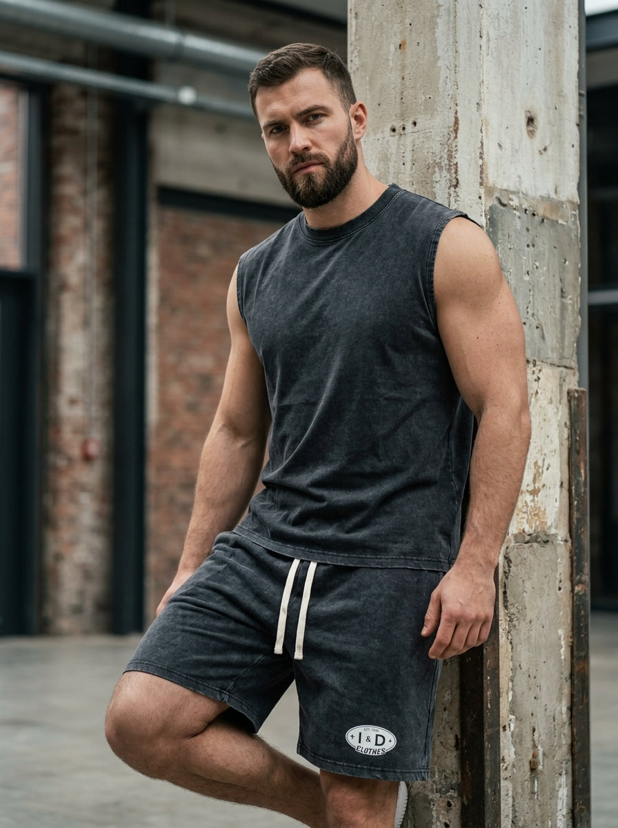 I&D Acid Wash Tank & Shorts Set — dark charcoal washed cotton, man leaning against wall, front view
